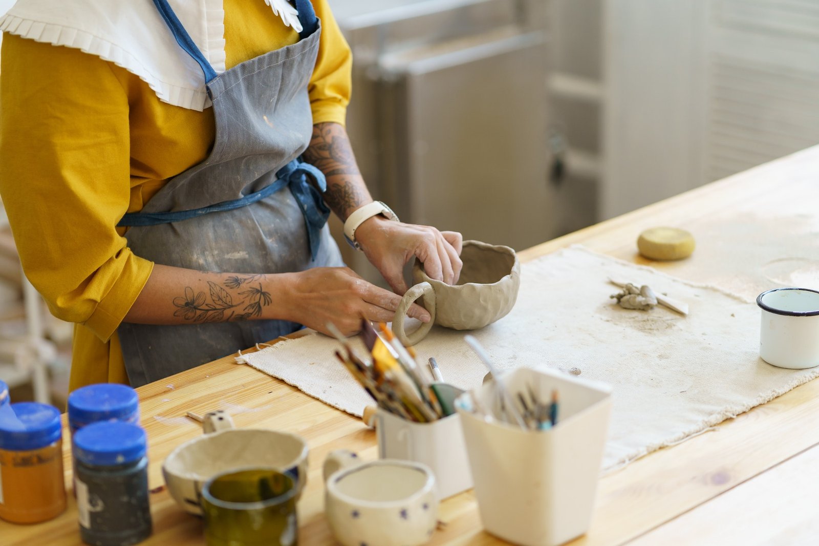 woman-in-apron-shaping-pottery-in-art-studio-making-clay-mug-during-ceramics-masterclass.jpg
